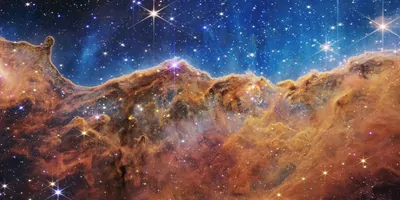 This landscape of “mountains” and “valleys” speckled with glittering stars is actually the edge of a nearby, young, star-forming region called NGC 3324 in the Carina Nebula