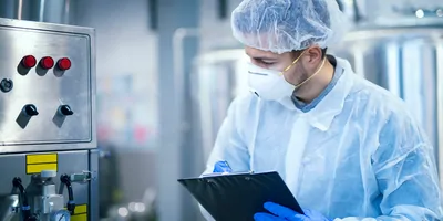 Scientist writes readings from lab equipment on clipboard