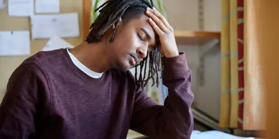 Stressed Male University Or College Student Studying With Laptop At Desk In Roo