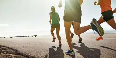People running on a road at sunset