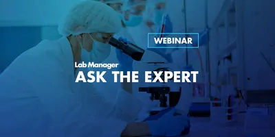 Lab staff dresses with PPE looking through a microscope