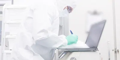 Scientist writes on a clipboard while reading results off a screen
