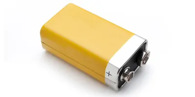A yellow 9v battery laying on a white background