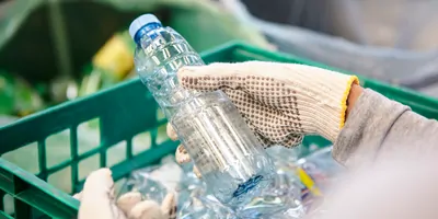 High angle view of waste management worker using work gloves holding plastic bottle