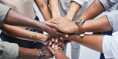 Group of people join hands in a huddle