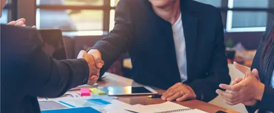 Businesspeople shake hands over a desk