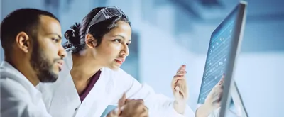 Two scientists work at a computer in the lab