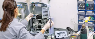 Woman works on a lab instrument with a soldering iron