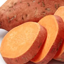 A whole and a sliced sweet potato on a white background