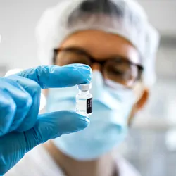 Pharma technician holding a vial of medication for inspection
