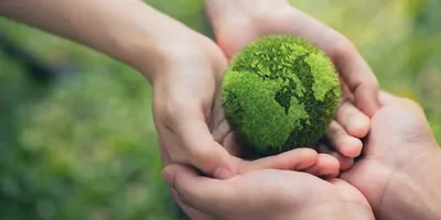Two sets of cupped hands holding a green globe