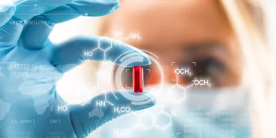 Woman wearing PPE and gloves holding a pill with holigraphic chemical symbols around it