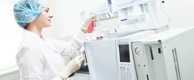 Female researcher putting flask into gas chromatograph