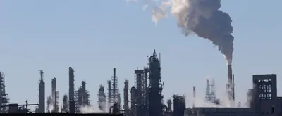 Image of oil refinery with smoke going up into the sky