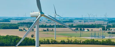 Image of Aerial close up of wind turbine with wind farm in background and substation