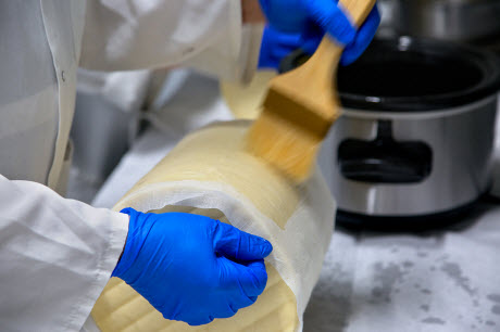 Lard is brushed on a clothbound cheddar