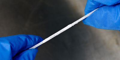 Gloved hands hold a label with patient identification on it