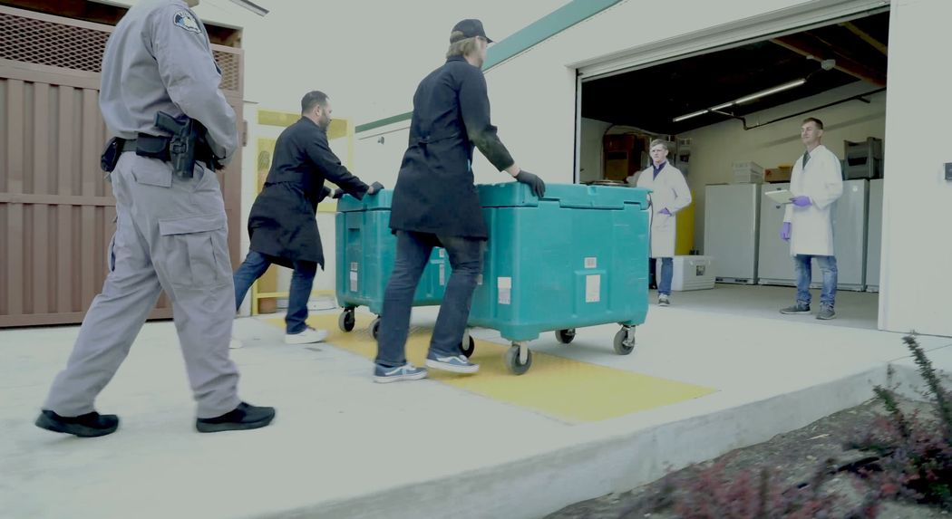 Multiple workers on loading dock pushing a wheeled cart into the lab Multiple workers on loading dock pushing a wheeled cart into the lab