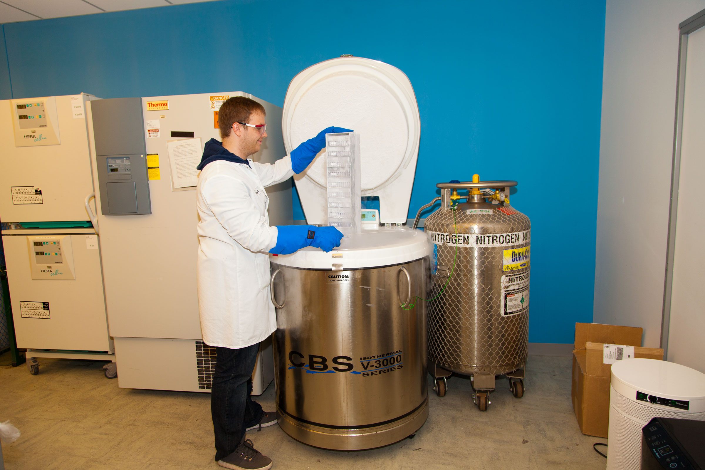 A young maile scientist stands by a large piece of equipment