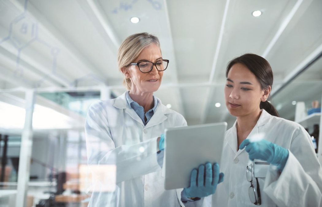 Two female scientists look at a tablet with an informatics solution on it in a contract laboratory Two female scientists look at a tablet with an informatics solution on it in a contract laboratory
