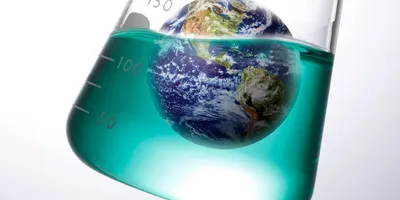 Image of the earth floating in green liquid in a scientific flask suggesting the importance of an environmental managment system (EMS) in the lab
