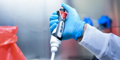 image of a gloved hand holding a pipette illustrating the use of a positive displacement pipette
