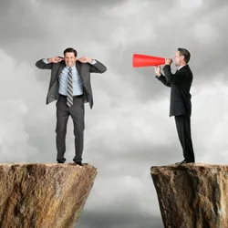 image of a businessman shouting through a megaphone at an employee across a chasm, illustrating the power of giving orders as requests