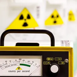 image of a Geiger Counter with radiation symbols in the background illutrating the importance of working safely with radioactive materials