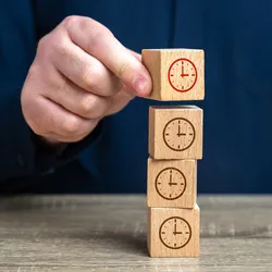 image of hand stacking blocks with clocks on them illustrating the concept of time chunking