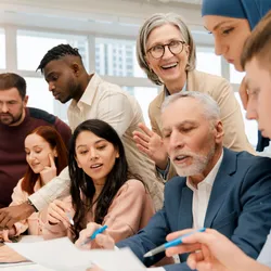 A diverse, multigenerational team engaged in a collaborative discussion in a bright office setting.