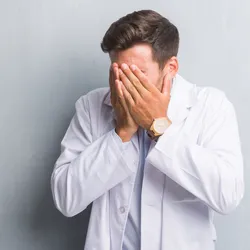 image of a lab manager covering his face suggesting that he is an intoverted manager
