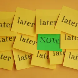 image of a group of yellow post-it notes on a wall all reading "later" with one green note that says "now" illustrating the concept of overcoming procrastination