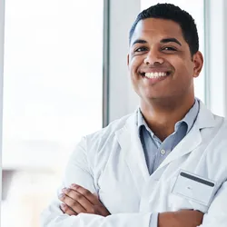 Smiling new laboratory manager in a white coat standing confidently in a modern lab environment