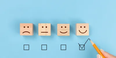4 bloacks ona blue background each with an expression on each from sad to happy a checkmark is below happy face illustrating the concept of creating engaged employees