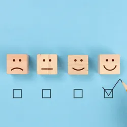 4 bloacks ona blue background each with an expression on each from sad to happy a checkmark is below happy face illustrating the concept of creating engaged employees