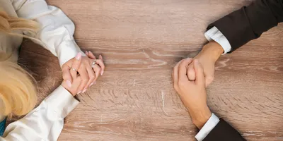 image of hands folded on a boardroom table opposite each other and suggesting the benefits of heatly workplace conflice