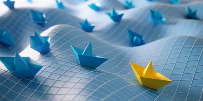 image of a yellow paper boat on a way surface followed by several blue boats illustrating the concept of leading versus managing
