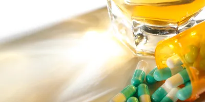 image of an alcoholoc beverage and spilled capsules on a counter illustrating the concept of ensuring a safe, heathy, and drug-free-workplace