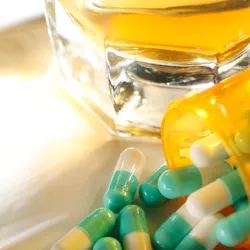 image of an alcoholoc beverage and spilled capsules on a counter illustrating the concept of ensuring a safe, heathy, and drug-free-workplace