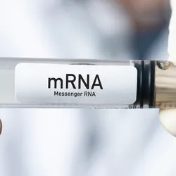 A scientist holds a syringe that reads "mRNA"