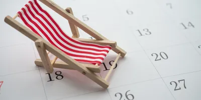 red and white striped beach chair sitting on top of a calendar illustrating the concept of summer vacation scheduling