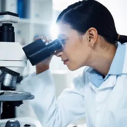 A scientist in a lab coat using a high-powered microscope, highlighting advancements in imaging technology that capture the full 3D orientation and position of molecules in cells.