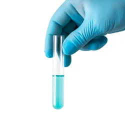 a gloved hand holding a test tube with blue liquid on a white background