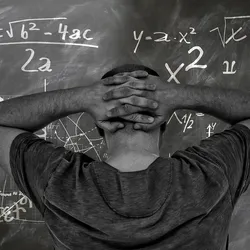 man standing in front of blackboard covered in physics and chemistry equations and illustrating the concelpt of what is physical science