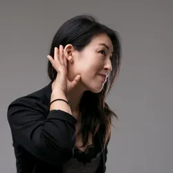 a woman with her hand behind her ear demonstrating the concelpt of active listening