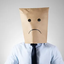 business man with paper bag ver head with a hand-drawn sad face illutrating the idea of coping with a job you dislike