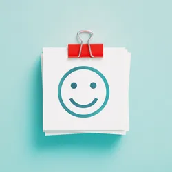 a post-it note with a smiling face against a light blue background suggesting providing positive feedback to achieve employee happiness