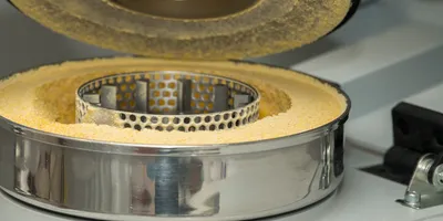 a laboratory mill with fine yellow powder inside and compartment lid raised illustrating lab mill and grider safety