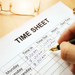 a time sheet on a wooden desh being completed byhand illustating the concelt of fixed schedules versus flexible work arrangements