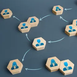 wooden tiles with images of employees on a blue table suggesting the concept of structured hiereachy vs flat organizational style